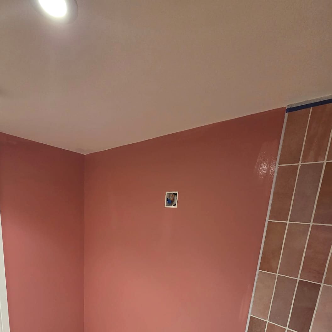 Bathroom walls painted dusty pink beside terracotta tiles